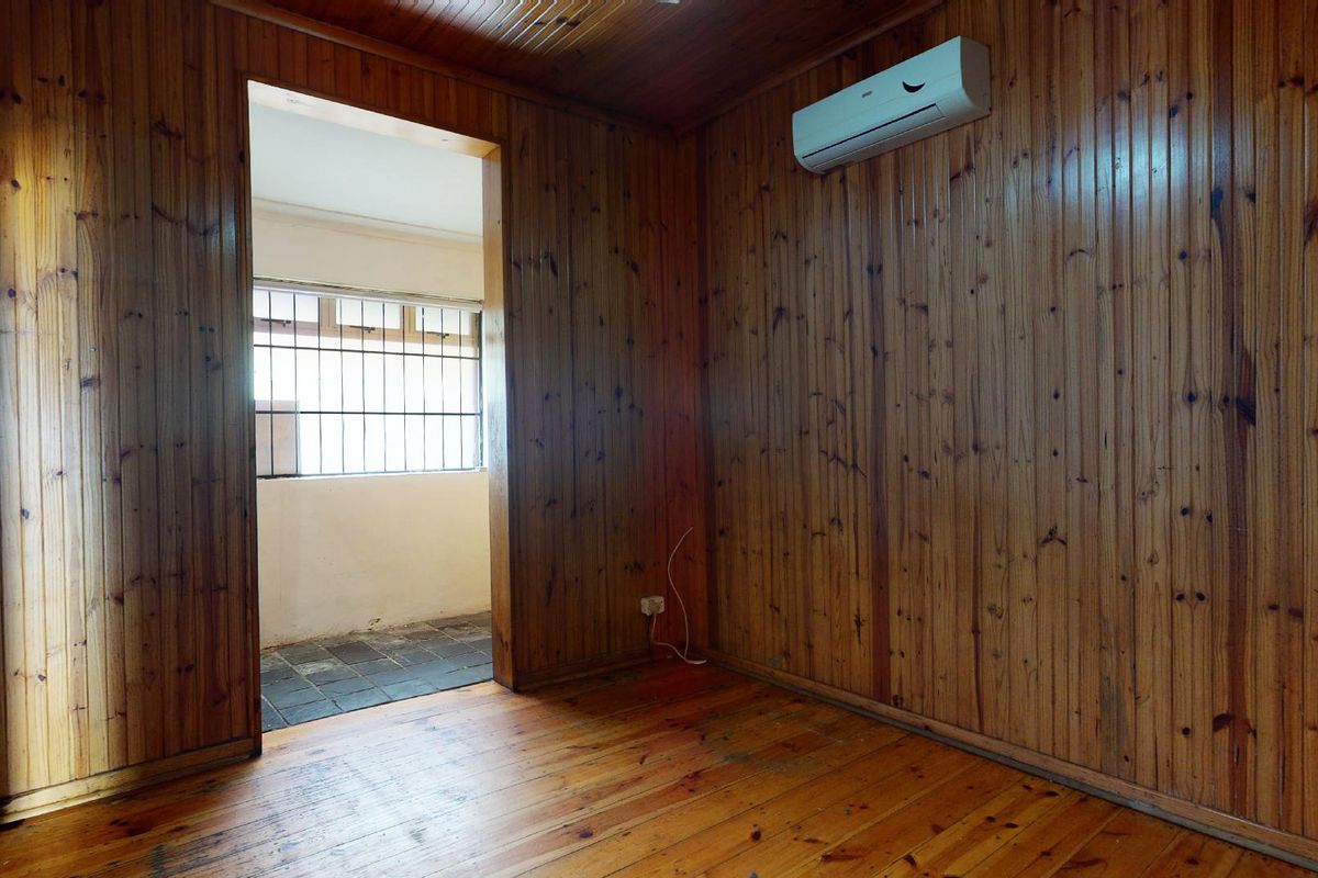 An empty bedroom featuring extensive timber wall paneling, timber ceiling, and timber flooring, equipped with a wall-mounted air conditioning unit.