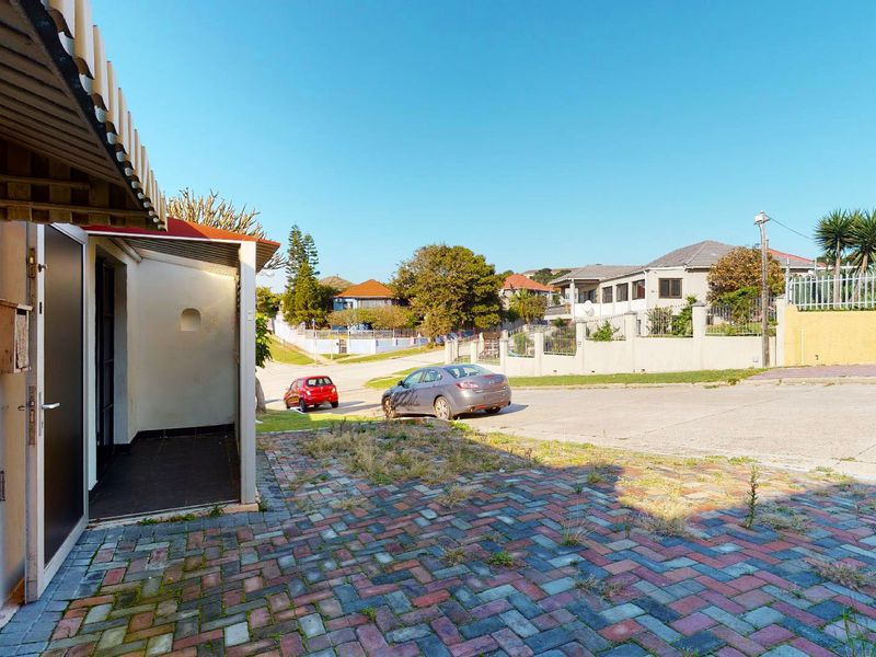 Front exterior view of the property featuring a paved driveway with a covered entrance area and surrounding boundary wall.