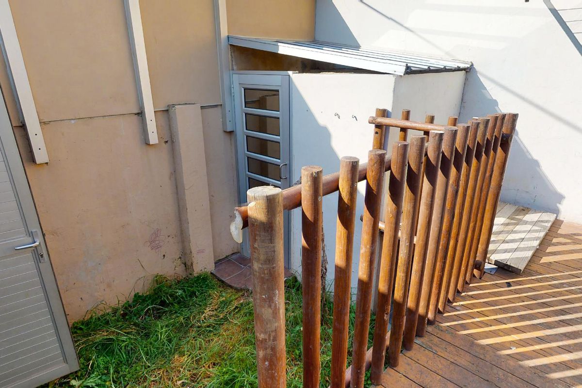 Rear exterior area featuring timber decking, a timber pole balustrade, and an access door with a lean-to roof structure.