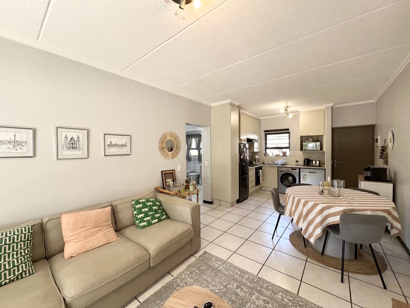 Open-plan living and dining area featuring tiled floors and a functional kitchen with built-in cabinetry and integrated appliances.