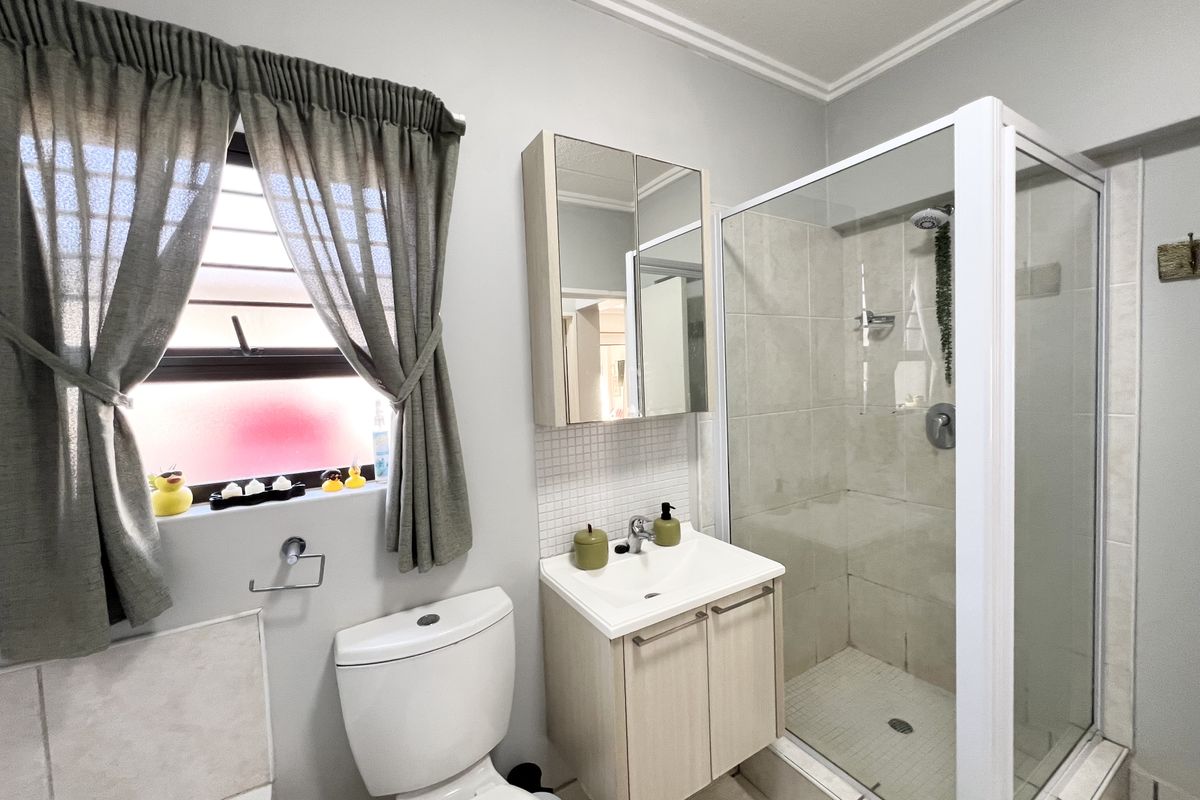 A well-maintained bathroom featuring a glass-enclosed shower, a modern vanity with a basin, a mirrored medicine cabinet, and a standard toilet.
