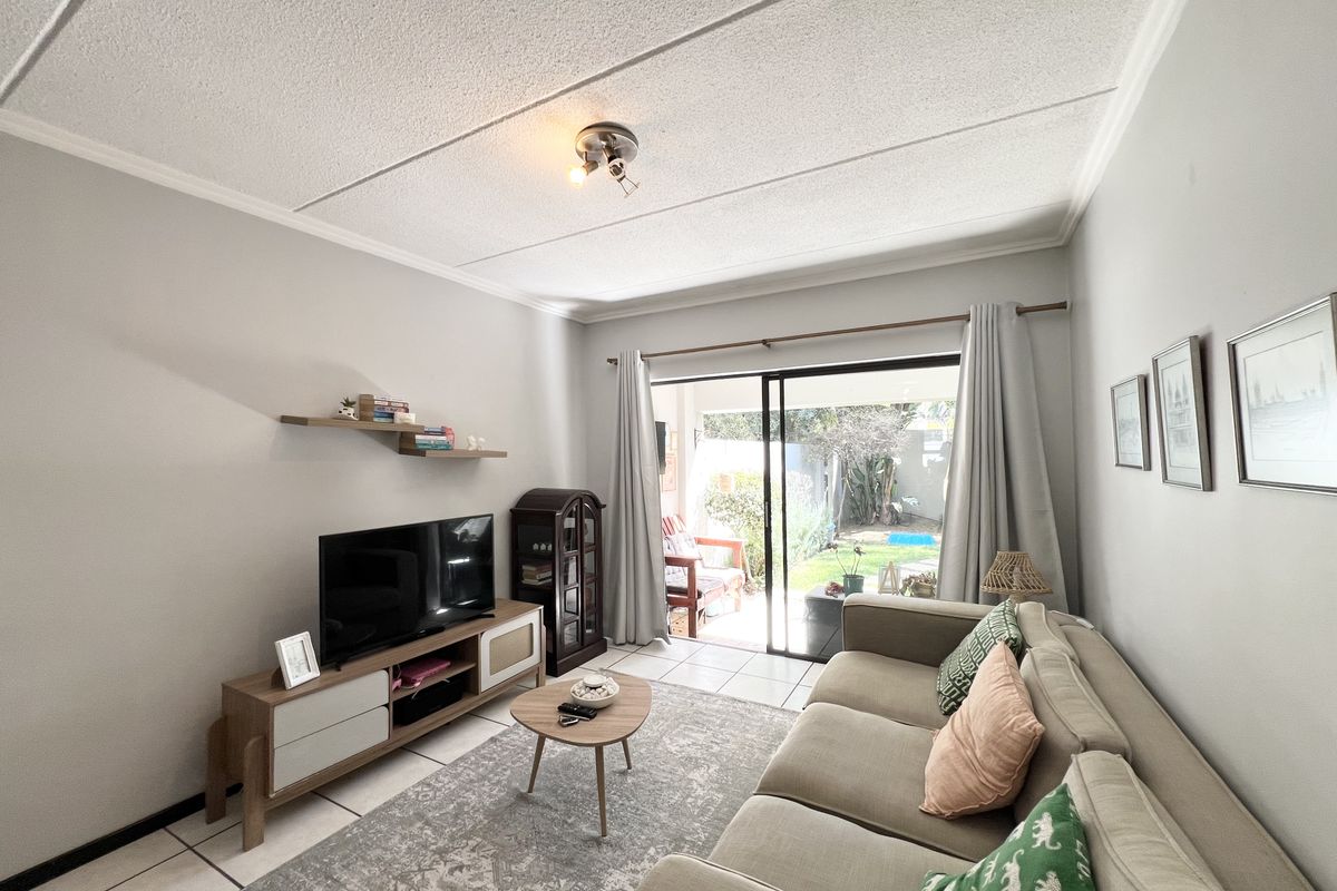A bright living room featuring tiled flooring, a textured ceiling, and a sliding glass door providing direct access to the outdoor patio area.