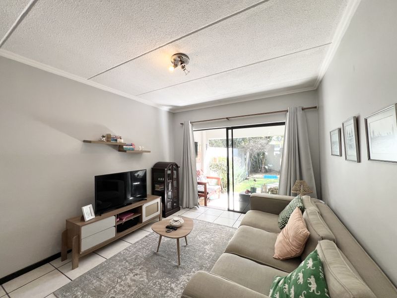 A bright living room featuring tiled flooring, a textured ceiling, and a sliding glass door providing direct access to the outdoor patio area.