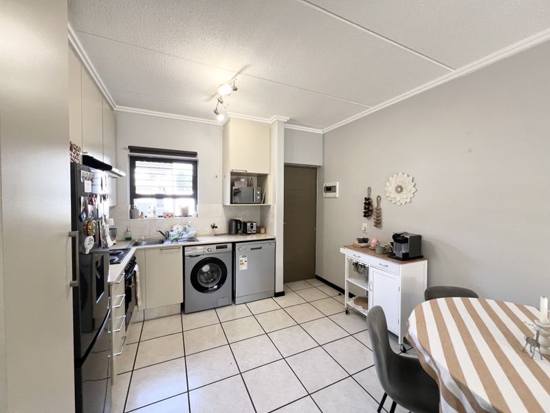 A functional kitchen featuring tiled flooring, built-in cabinetry, integrated appliances, and a window providing natural light.