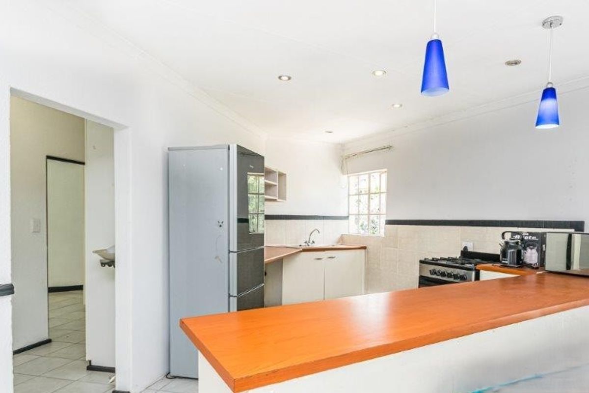 Functional kitchen featuring a breakfast bar, built-in cabinetry, gas stove, and tiled backsplash, offering a practical layout for daily meal preparation.