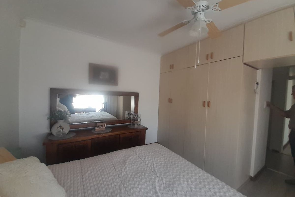 A bedroom featuring built-in cupboards with overhead storage and a ceiling fan.
