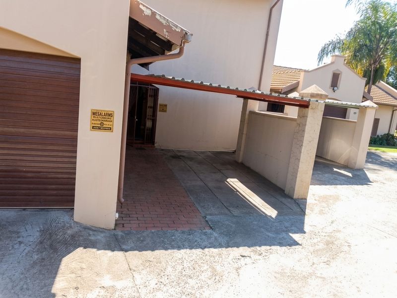Front exterior view of the townhouse featuring a garage, a covered carport, and paved driveway access.