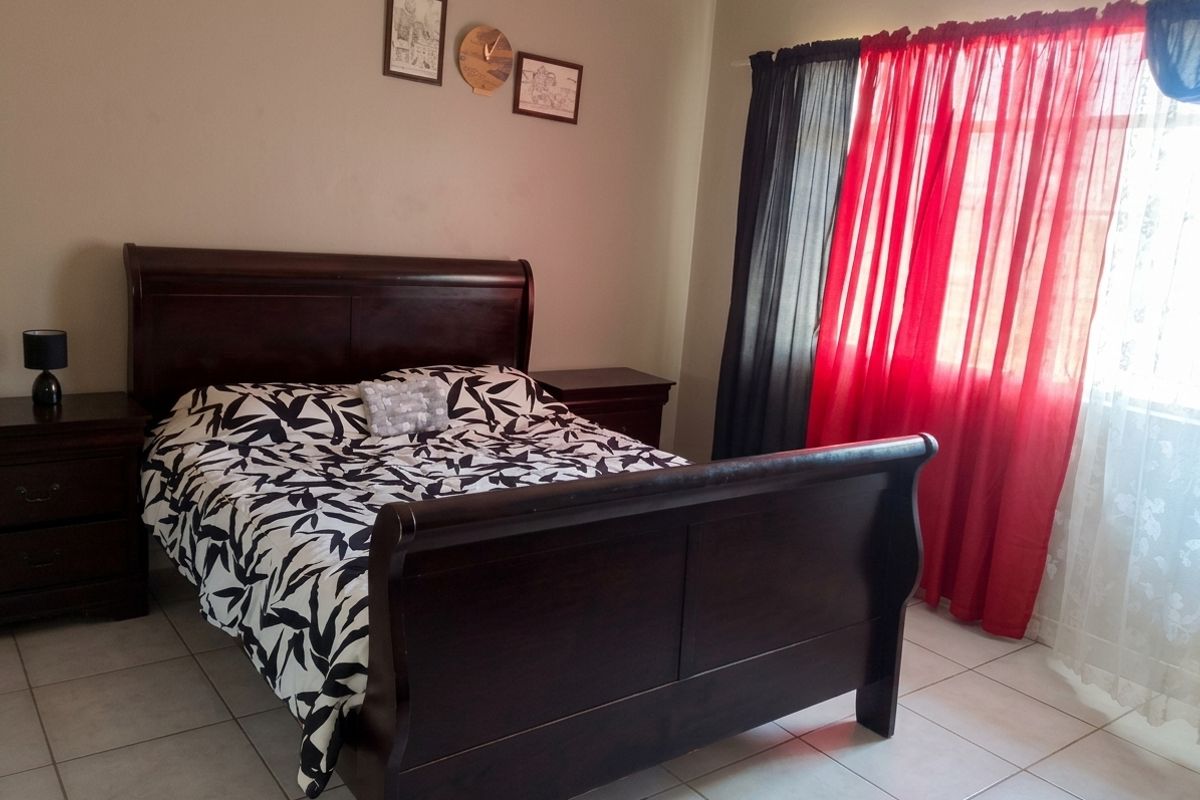A functional bedroom featuring neutral wall tones and durable tiled flooring, providing a comfortable and practical living space.