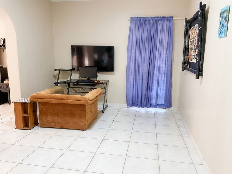 A living area featuring neutral wall paint, ceramic floor tiles, and a sliding glass door providing access to the exterior.