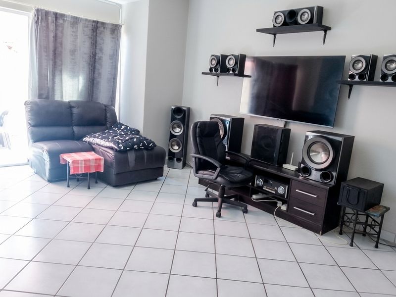 A living room featuring ceramic floor tiles and a sliding glass door providing access to the exterior.