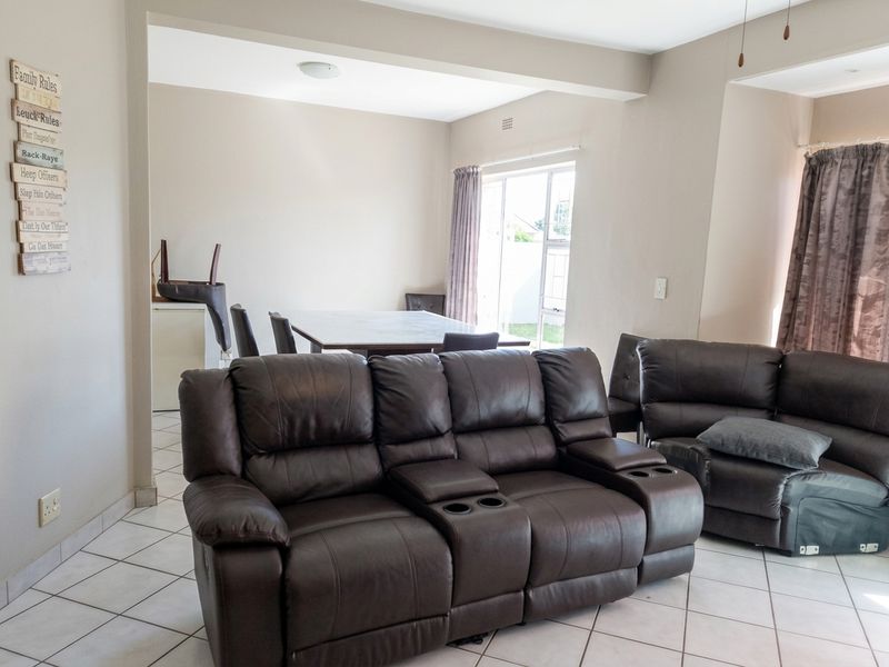 Open plan living and dining area featuring neutral wall tones, tiled flooring, and a sliding glass door providing natural light.