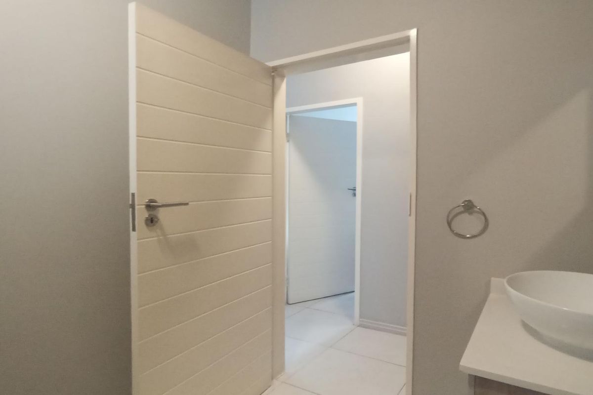 A clean and modern bathroom featuring a white vessel sink, tiled flooring, and neutral wall finishes with internal door access.