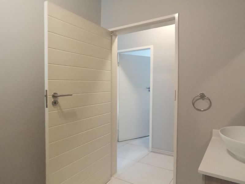 A clean and modern bathroom featuring a white vessel sink, tiled flooring, and neutral wall finishes with internal door access.