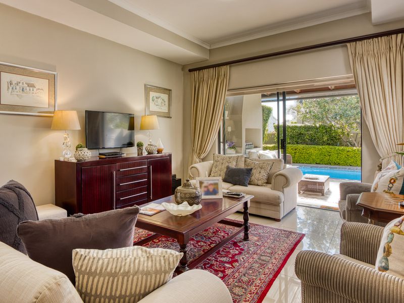 A well-maintained living room featuring tiled floors, recessed ceiling details, and large sliding glass doors providing seamless access to the outdoor pool area.