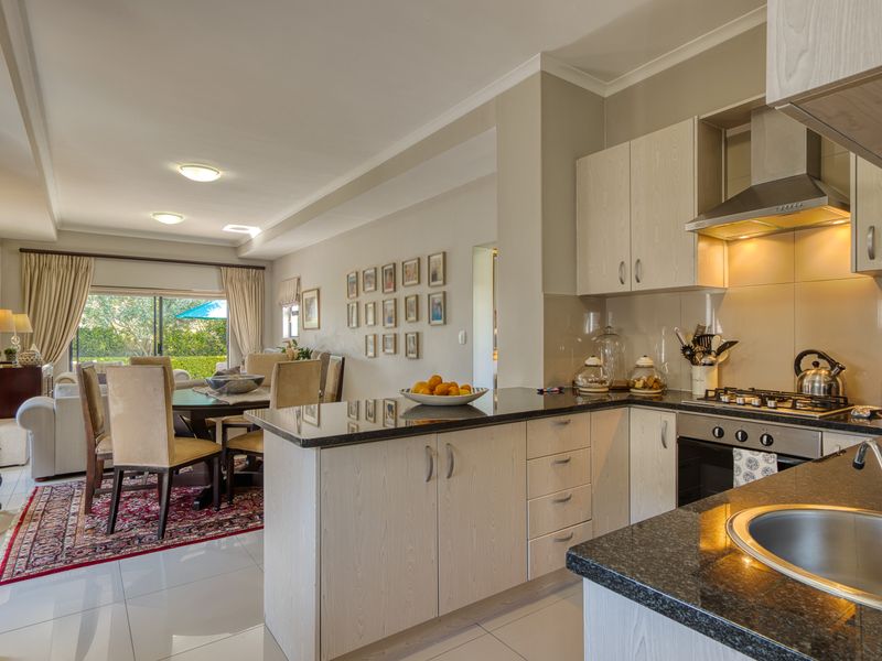 Open-plan kitchen and dining area featuring modern cabinetry, granite countertops, integrated appliances, and direct access to the outdoor patio through sliding glass doors.