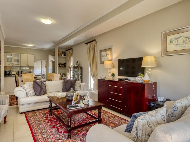 Spacious open-plan living area featuring tiled floors, integrated kitchen cabinetry, and built-in shelving, creating a cohesive and functional living and dining space.