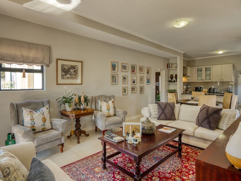 Spacious open-plan living area featuring tiled floors, neutral walls, and a functional kitchen with built-in cabinetry and integrated appliances.