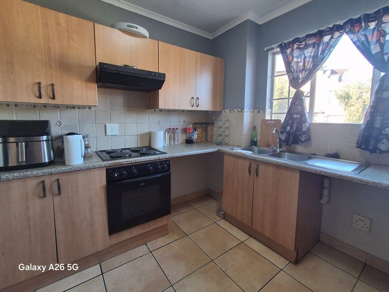 Functional kitchen featuring laminate cabinetry, built-in oven with hob, extractor fan, double bowl sink, and tiled flooring.