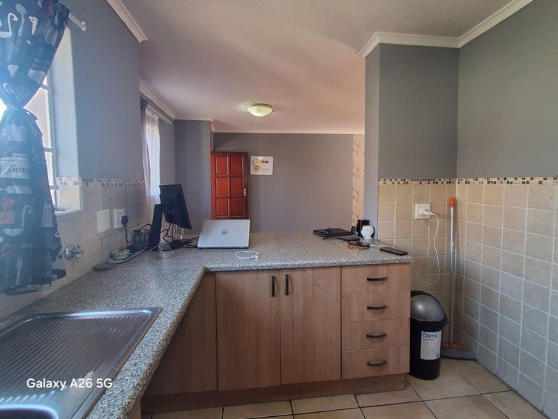 A functional kitchen featuring laminate cabinetry, granite-look countertops, tiled backsplash, and ceramic flooring, offering a practical workspace with neutral wall finishes.