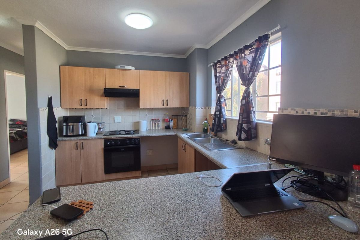 Functional kitchen featuring light wood cabinetry, granite-look laminate countertops, built-in oven with extractor fan, and a double sink with tiled backsplash.
