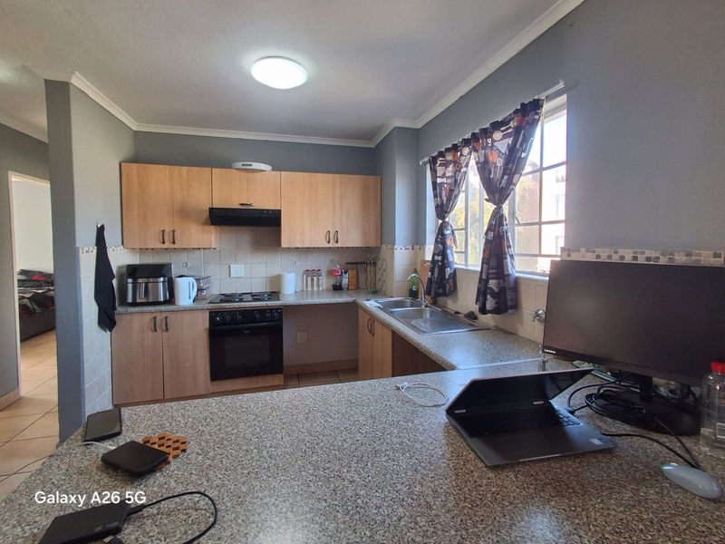 Functional kitchen featuring light wood cabinetry, granite-look laminate countertops, built-in oven with extractor fan, and a double sink with tiled backsplash.