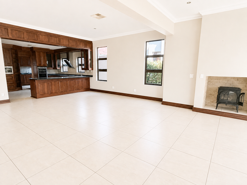 Spacious open-plan living area featuring tiled floors, a built-in wooden kitchen with granite countertops, and a cozy cast iron fireplace with stone surround.