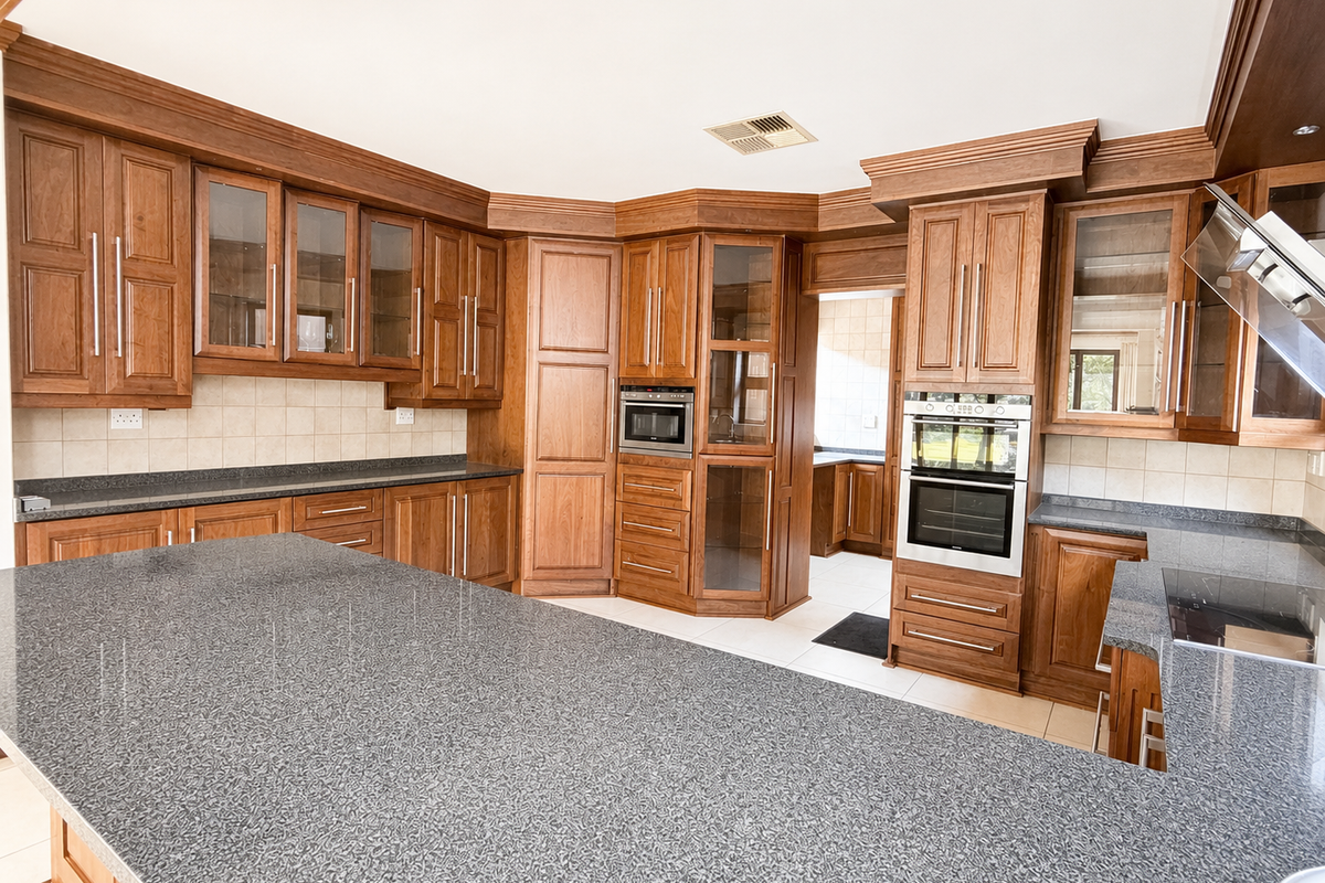 Spacious kitchen featuring extensive wooden cabinetry, granite countertops, a large central island, and integrated appliances including a built-in oven and microwave.