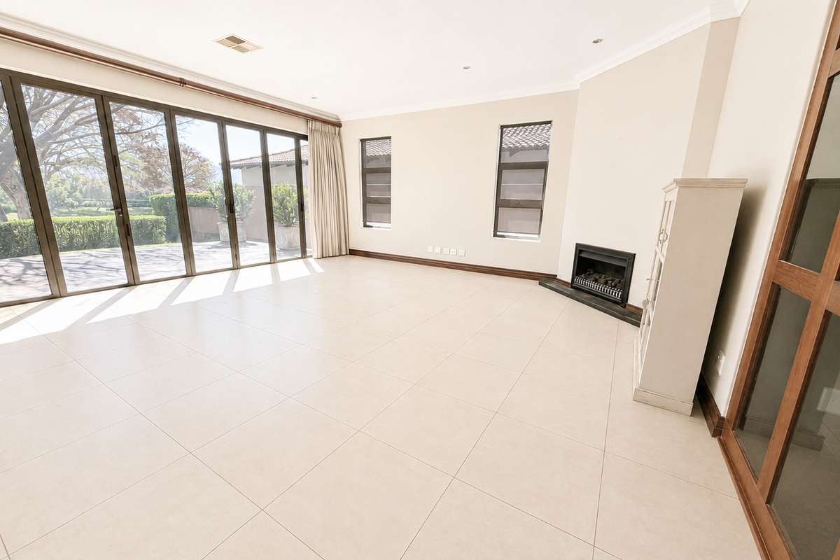 Spacious, light-filled living room featuring large sliding glass doors, neutral tiled flooring, and a built-in fireplace, offering a seamless transition to the outdoor area.