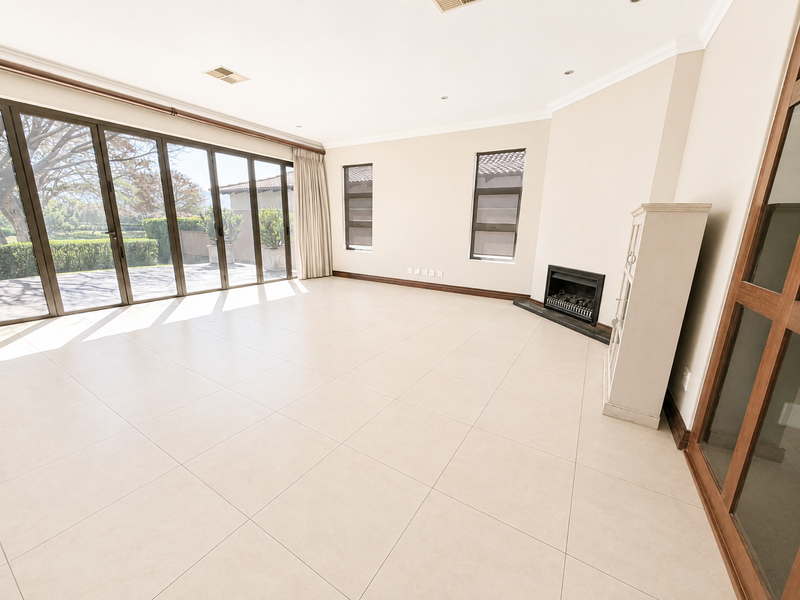 Spacious, light-filled living room featuring large sliding glass doors, neutral tiled flooring, and a built-in fireplace, offering a seamless transition to the outdoor area.