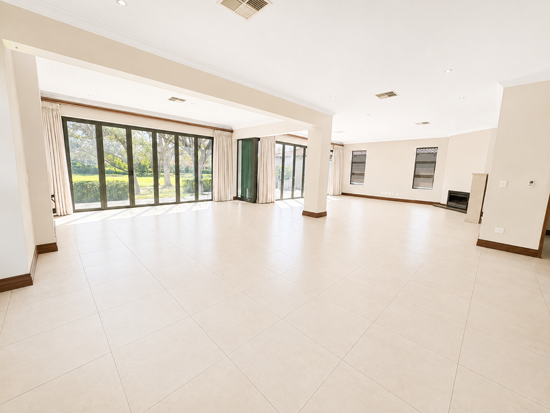A spacious, light-filled open-plan living area featuring large sliding glass doors, neutral tiled flooring, and a built-in fireplace.