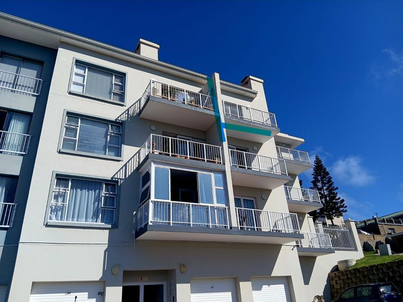 Rear elevation of a multi-story apartment building featuring private balconies with metal railings and ground-level garage access.