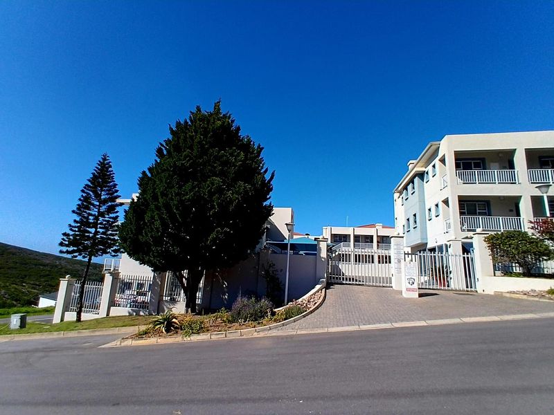 Front exterior view of the apartment complex featuring a paved driveway, secure gated entrance, and multi-level balconies.
