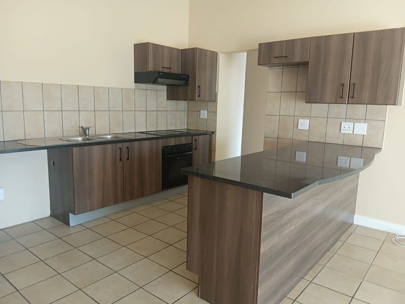 Modern kitchen featuring dark wood cabinetry, granite countertops, built-in oven, hob, extractor fan, and a functional breakfast bar island.