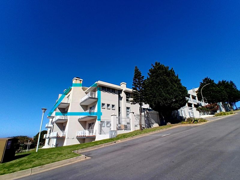 Exterior view of a multi-story apartment building featuring private balconies, metal railings, and a paved driveway approach.