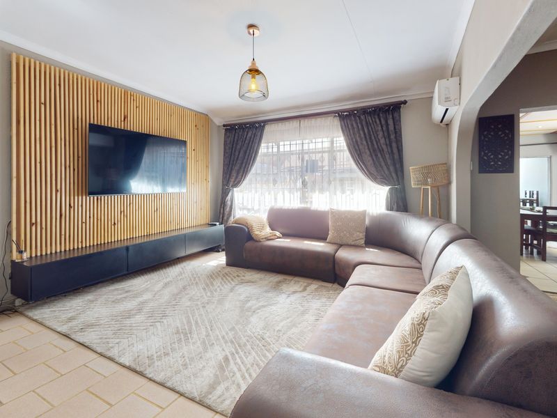 A well-maintained living room featuring a modern timber slat feature wall, tiled flooring, and a split-system air conditioner for climate control.