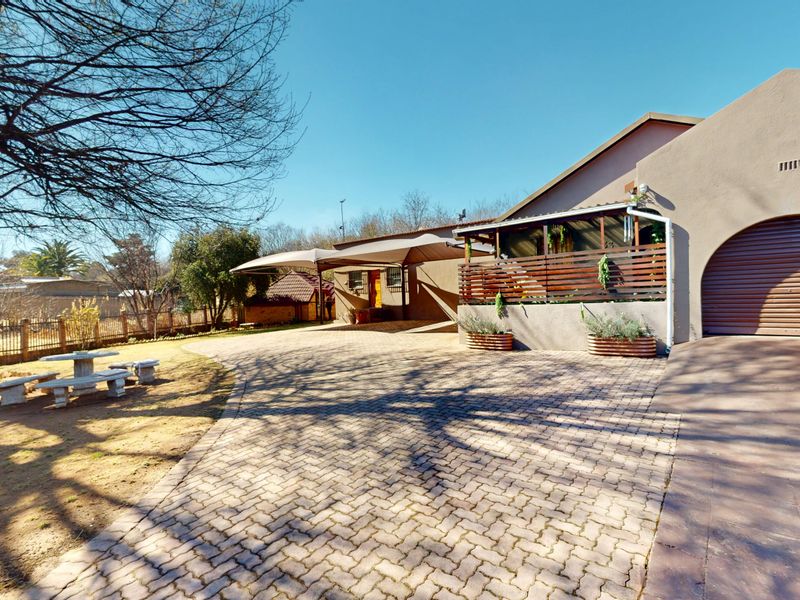 Front exterior view featuring a paved driveway, garage access, and a covered patio area with timber screening.