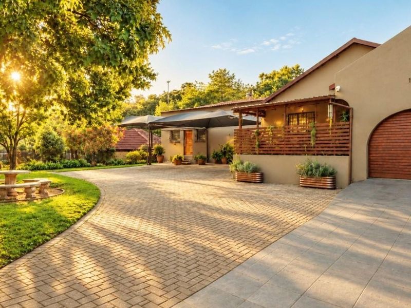 A well-maintained front exterior featuring a paved driveway, arched garage entrance, and a covered patio area set within a landscaped garden.
