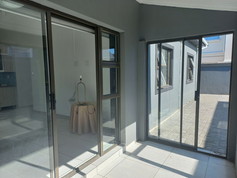 A covered patio area featuring tiled flooring and large sliding glass doors that provide access to the interior and the paved rear yard.