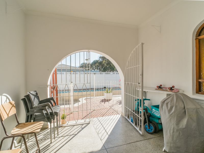 A covered patio area featuring an arched security gate providing direct access to the outdoor pool area.
