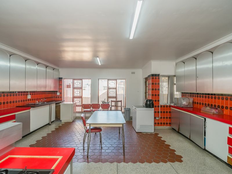 Spacious kitchen featuring extensive built-in cabinetry, vibrant red tiled backsplash, and a unique hexagonal tiled floor area, offering significant potential for modernization.