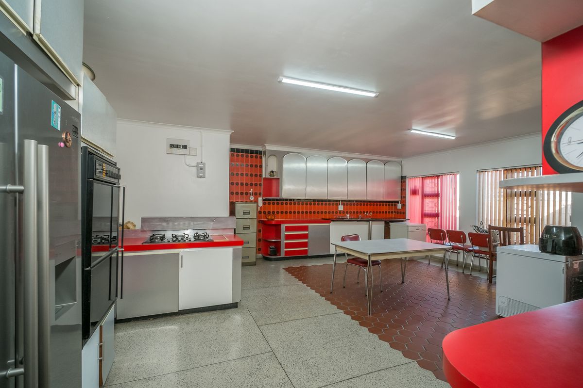 Spacious kitchen featuring retro cabinetry, a gas hob, built-in oven, and a combination of tiled flooring, offering significant potential for modern renovation.