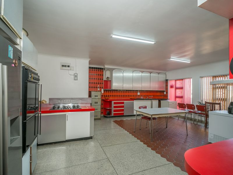 Spacious kitchen featuring retro cabinetry, a gas hob, built-in oven, and a combination of tiled flooring, offering significant potential for modern renovation.