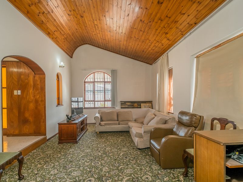 Spacious living room featuring a high vaulted timber ceiling, arched architectural details, and large windows providing natural light.