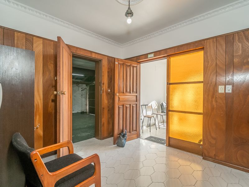 A spacious hallway featuring classic wood paneling, decorative ceiling cornicing, and tiled flooring, providing access to multiple rooms.