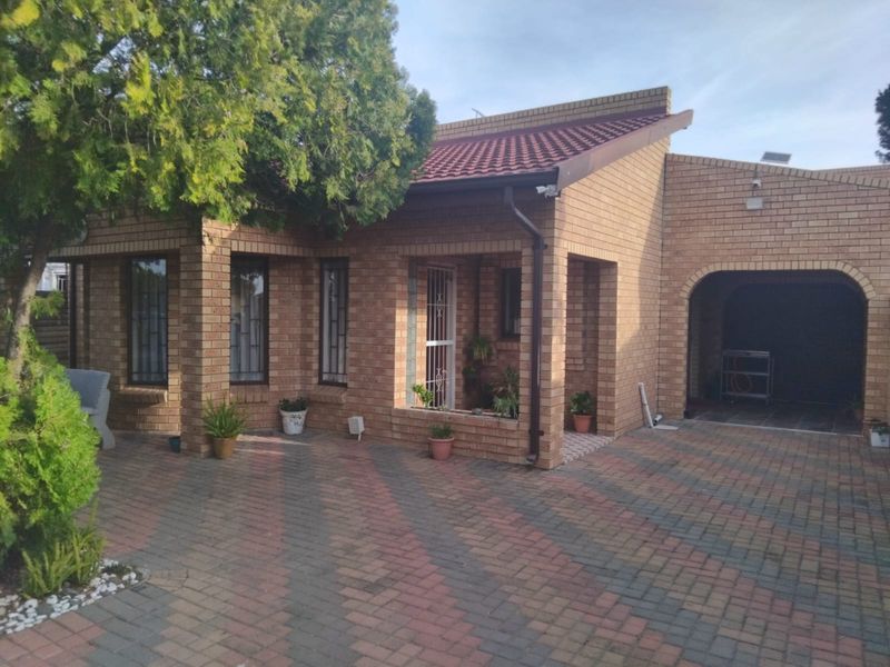 A well-maintained face brick house featuring a paved driveway, covered entrance, and integrated carport, showcasing classic architectural design and secure exterior finishes.
