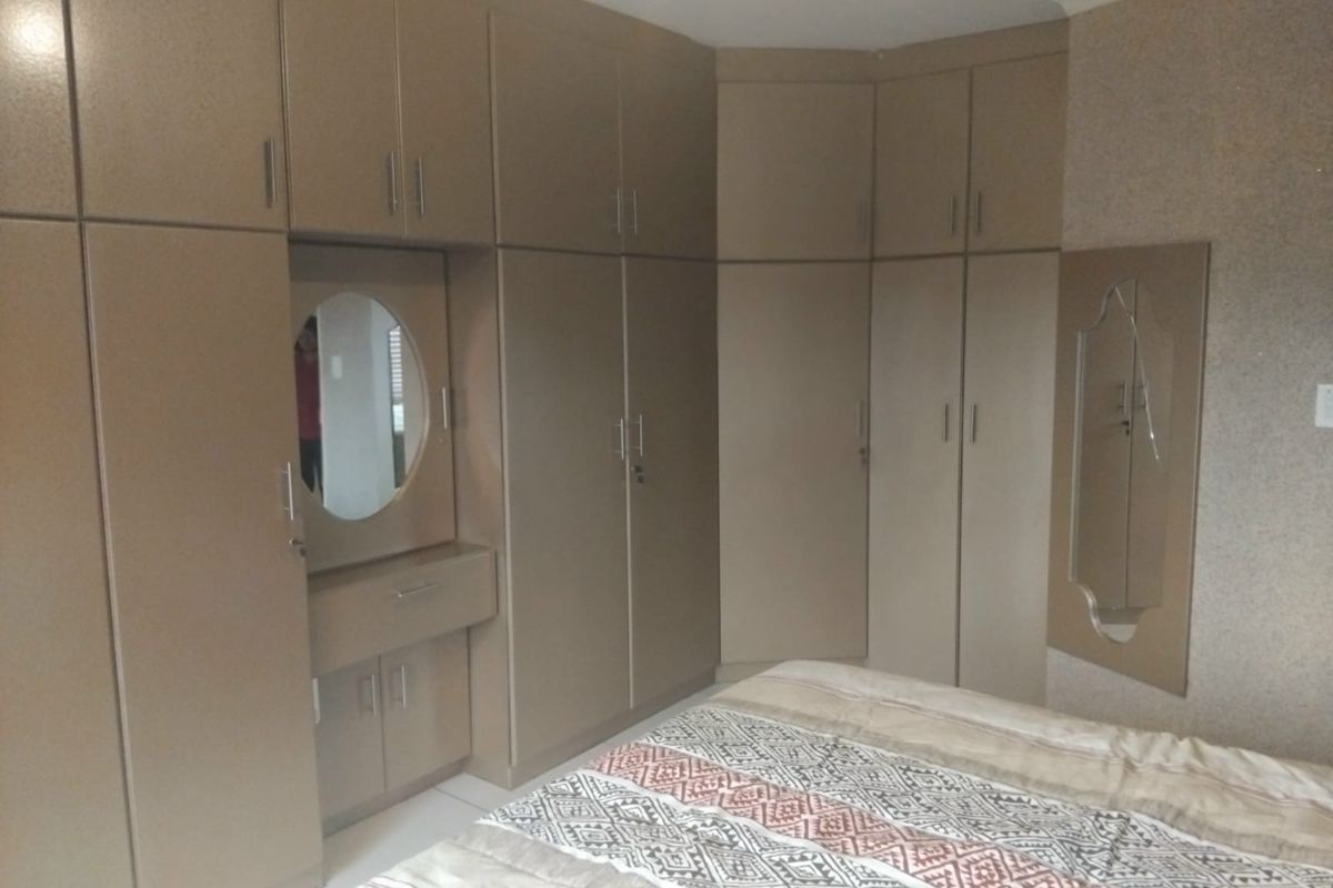 A bedroom featuring extensive built-in cabinetry with a integrated vanity station and mirror, providing ample storage and a functional layout.
