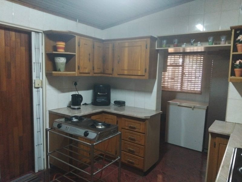 A functional kitchen featuring traditional wooden cabinetry, laminate countertops, and tiled splashbacks, offering a dated aesthetic with potential for modern renovation.