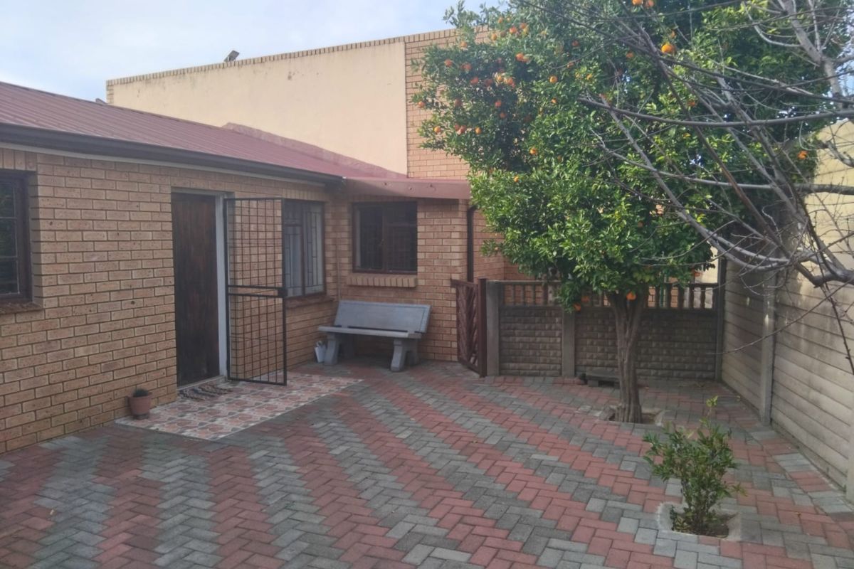 A private rear courtyard featuring brick exterior walls, paved flooring in a herringbone pattern, and secure access points.