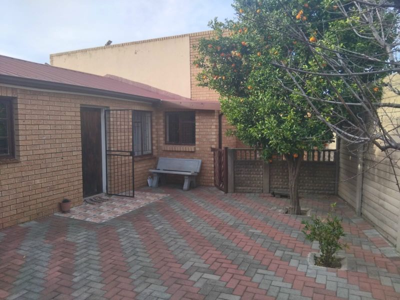 A private rear courtyard featuring brick exterior walls, paved flooring in a herringbone pattern, and secure access points.