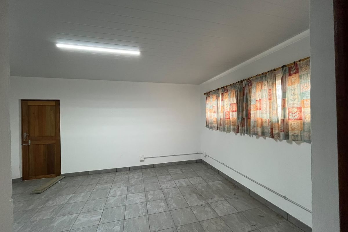 An empty, neutrally painted room featuring tiled flooring, a timber door, and exposed electrical conduit, offering a blank canvas for renovation.